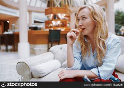 Woman enjoying snack and sitting at the hotel lobby