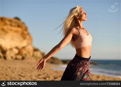Woman enjoying the sunset on a beautiful beach in Cadiz, Andalusia, Spain. Young female opening arms and breathing the sea air.. Woman enjoying the sunset on a beautiful beach