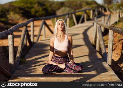 Woman enjoying the sunset on a beautiful beach in Cadiz, Andalusia, Spain. Caucasian female practicing yoga on wooden bridge.. Caucasian female practicing yoga on wooden bridge.