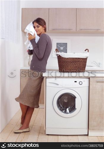 woman enjoys a smell of the washed things in laundry room