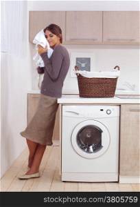 woman enjoys a smell of the washed things in laundry room