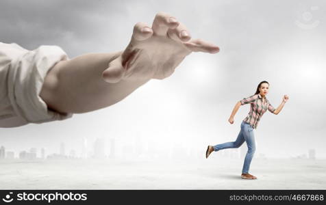 Woman escape from hand. Young woman in casual running away from big hand