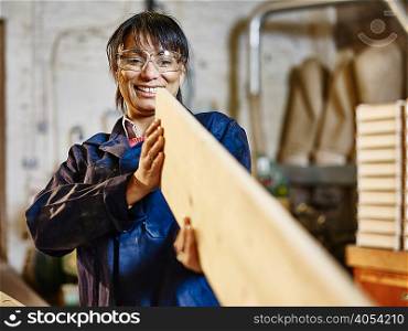 Woman examining straightness of wood plank in printing workshop