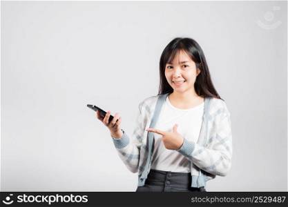 Woman excited celebrating win yes, great news on smartphone she pointing finger to mobile phone studio shot isolated white background, young female smiling having success after received promotion
