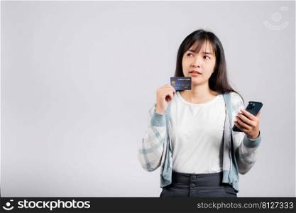 Woman excited smiling hold mobile phone and plastic debit credit bank card for payment studio shot isolated white background, happy young female using smartphone buy and pay online shopping