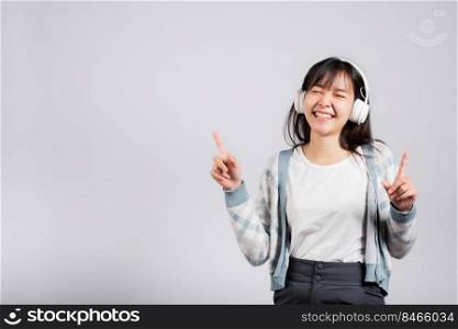 Woman excited smiling listening to music radio in bluetooth headphones and dancing with smartphone studio shot isolated white background, happy Asian young female Karaoke online app in mobile phone