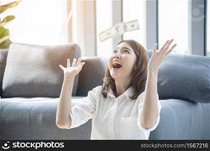 Woman excited with money dollar banknote rain fall. Happy start up business woman got winner lucky draw reward rich millionaire with happiness. Financial success woman investment.