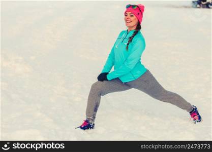 Woman exercising among snow and ice, how to work out in cold environment, fitness nature fashion concept. Woman exercising among snow and ice
