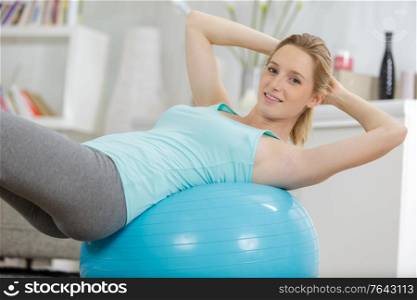 woman exercising her abs on a blue pilates ball