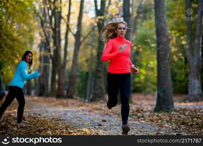 Woman Exercising in Public Park with Personal Trainer in the Fall. Trainer Cheering and Woman Running.. Woman Exercising in Public Park with Personal Trainer. Trainer Cheering and Woman Running