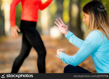 Woman Exercising in Public Park with Personal Trainer in the Fall. Trainer Counting Jumps.. Woman Exercising in Public Park with Personal Trainer.