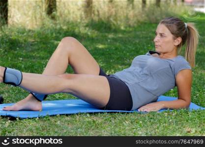 woman exercising outdoors with weights on her legs
