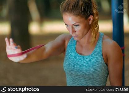Woman Exercising With Elastic Band Outdoors in The Fall, in Public Park