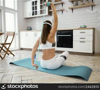 woman exercising with elastic band while listening music 2