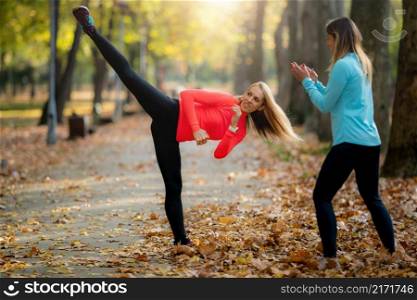 Woman Exercising with Personal Trainer in Public Park in the Fall.. Woman Exercising with Personal Trainer in Public Park.