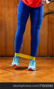 Woman exercising with rubber resistance band at home