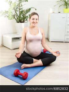 Woman expecting baby doing yoga exercise on mat at home
