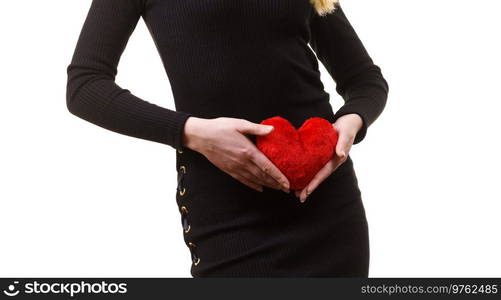 Woman expecting baby. Pregnant female holding small heart shaped pillow on her stomach.. Woman expecting baby with heart pillow