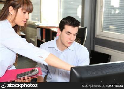 Woman explaining something on a computer to her colleague