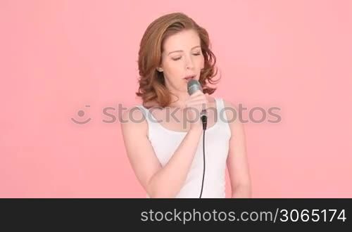 Woman Explaining Something Using Microphone, isolated studio portrait on pink with copyspace