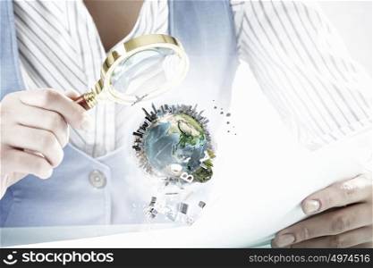 Woman exploring Earth planet. Close view of businesswoman examining Earth planet with magnifying glass. Elements of this image are furnished by NASA