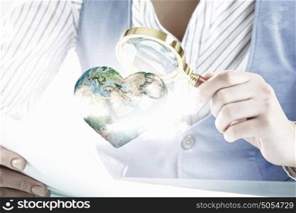 Woman exploring Earth planet. Close view of businesswoman examining Earth planet with magnifying glass. Elements of this image are furnished by NASA