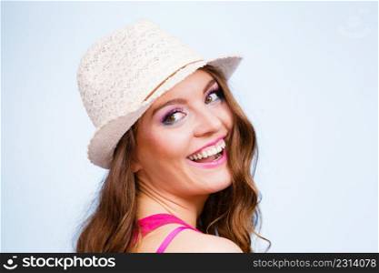 Woman face colorful eyes makeup summer straw hat on head smiling having fun closeup. Summer holidays and happiness, studio shot on blue. Woman in summer straw hat on head smiling