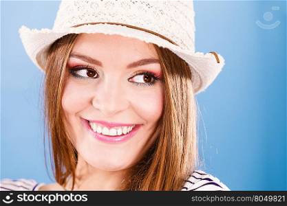 Woman face colorful eyes makeup summer straw hat on head smiling having fun closeup. Summer holidays and happiness, studio shot on blue