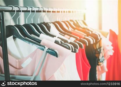 Woman fashion clothes of different colors clothing on hangers at the showroom / Hanging clothes closet rack