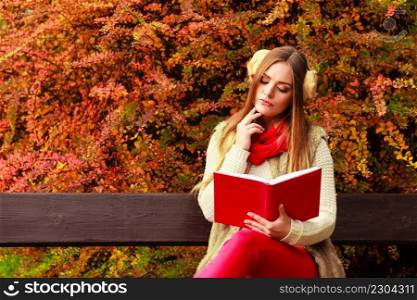 Woman fashion girl relaxing in autumnal park reading book sitting on bench. Fall lifestyle concept.. Woman relaxing in autumnal park reading book 