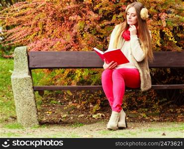 Woman fashion girl relaxing in autumnal park reading book sitting on bench. Fall lifestyle concept.. Woman relaxing in autumnal park reading book