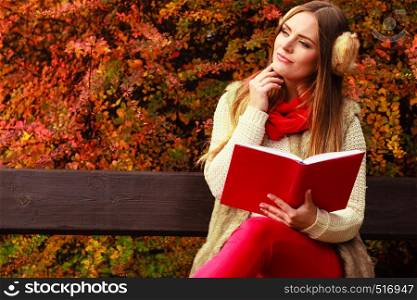 Woman fashion girl relaxing in autumnal park reading book sitting on bench. Fall lifestyle concept.. Woman relaxing in autumnal park reading book
