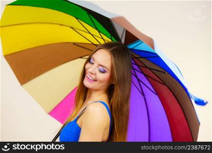 Woman fashion summer attractive girl standing under colorful rainbow umbrella, on gray. Positive smiling female model. Forecasting and weather season concept. Woman standing under colorful rainbow umbrella