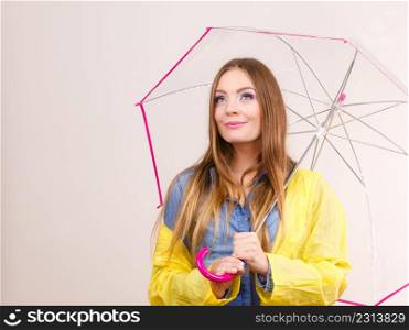 Woman fashionable rainy girl wearing waterproof yellow coat holding transparent umbrella. Meteorology, forecasting and weather season concept. Woman wearing waterproof coat holding umbrella