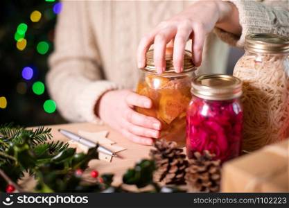 Woman Fastening Lids On Homemade Jars Of Preserved Fruit For Eco Friendly Christmas Gift