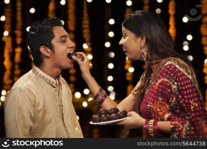 Woman feeding gulab jamun to her brother