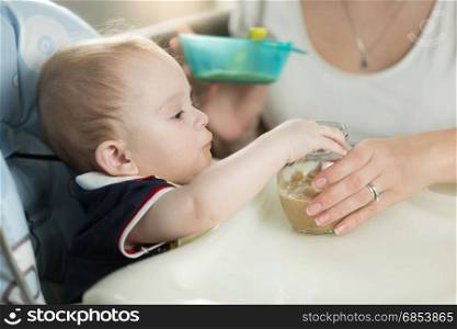 Woman feeding her baby from spoon with apple sauce