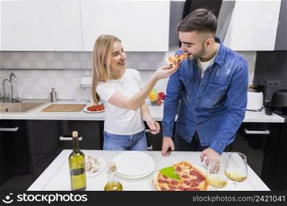 woman feeding man with pizza kitchen