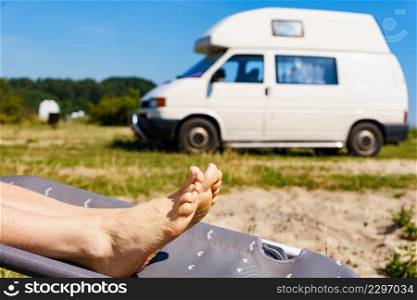 Woman feet on deck chair. Female relaxing enjoying sun on sunny summer day in front of rv c&ervan... Female resting in front of caravan