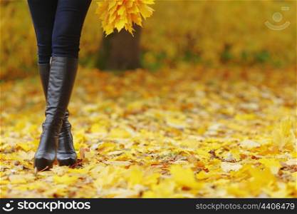 Woman feet with black boots in autumn park