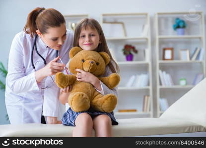 Woman female doctor examining little cute girl with toy bear