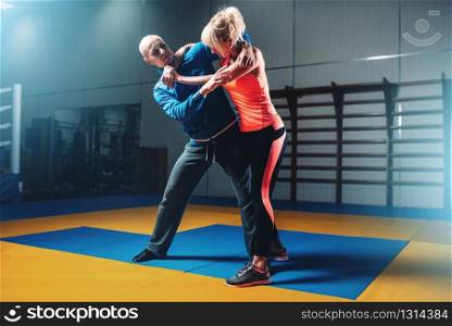 Woman fights with man on self-defense training, fighting workout in gym, martial art
