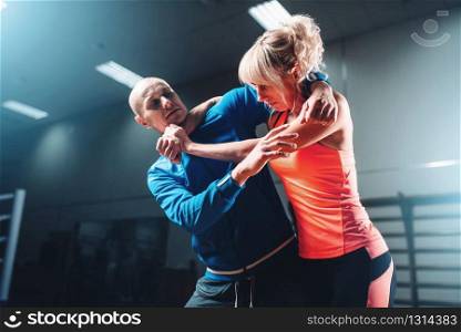 Woman fights with man, self defense technique, self-defense workout with personal trainer in gym, martial art. Woman fights with man, self defense technique