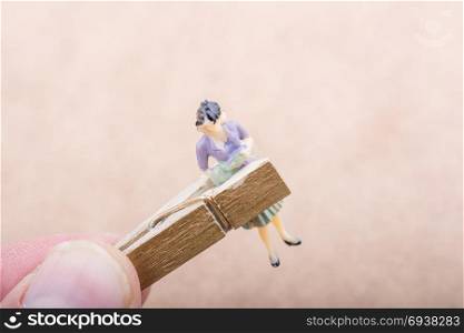 Woman figurine trapped in a clothespin on ground