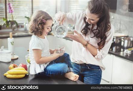 Woman filling a glass with water for her little daughter