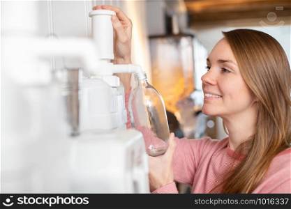 Woman Filling Container With Cleaning Product In Plastic Free Grocery Store