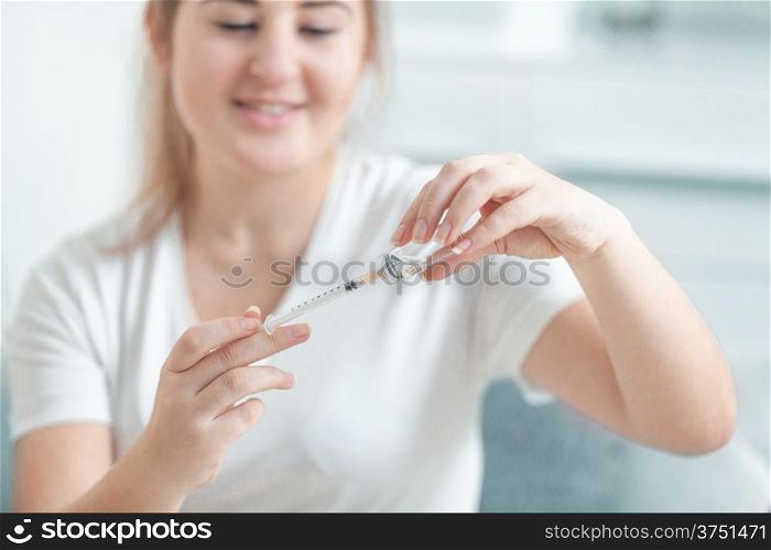 Woman filling insulin syringe with drug from ampule