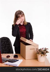 Woman fired from her job at the office and collect personal belongings and hand wipes tears. Dismissed girl in office wipes tears and collects things
