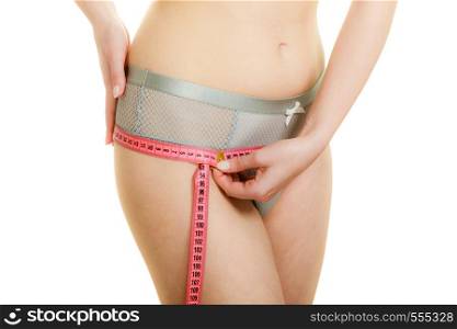 Woman fit girl in lingerie measuring her hips with measure tape closeup. Part of female body. Weight loss dieting concept.. Woman in lingerie measuring her hips with measure tape.