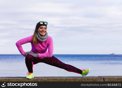 Woman fitness sport girl training outdoor in cold weather. Woman athlete girl training wearing warm sporty clothes outside by seaside in cold weather. Sports and activities in winter or autumn time.
